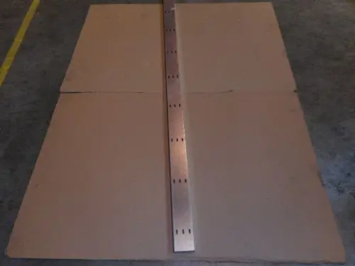 Zwei große Platten aus Pappe mit einer metallenen Leiste in der Mitte, die Löcher aufweist. Das Bild zeigt ein Arrangement, möglicherweise für eine Remeha-Produktion.